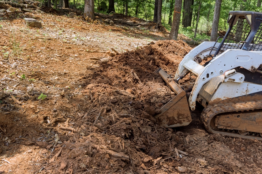 Tractor leveling ground at an earthmoving site in preparation for construction work is backyard